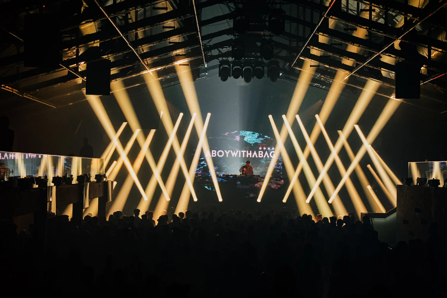 A DJ set under stage lights in front of a crowd